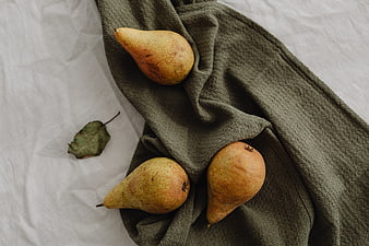 Three ripe pears on a green textured cloth