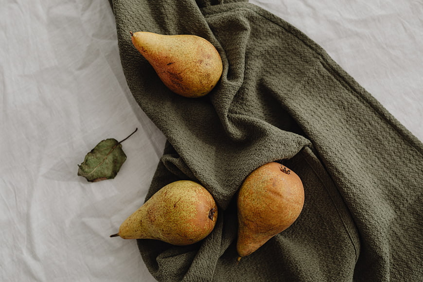Three ripe pears on a green textured cloth