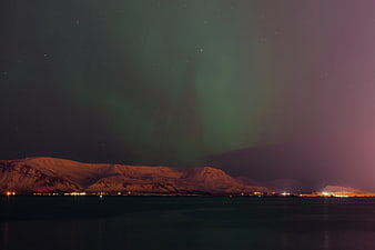 Aurora Borealis over Snowy Mountains and Coastal Town