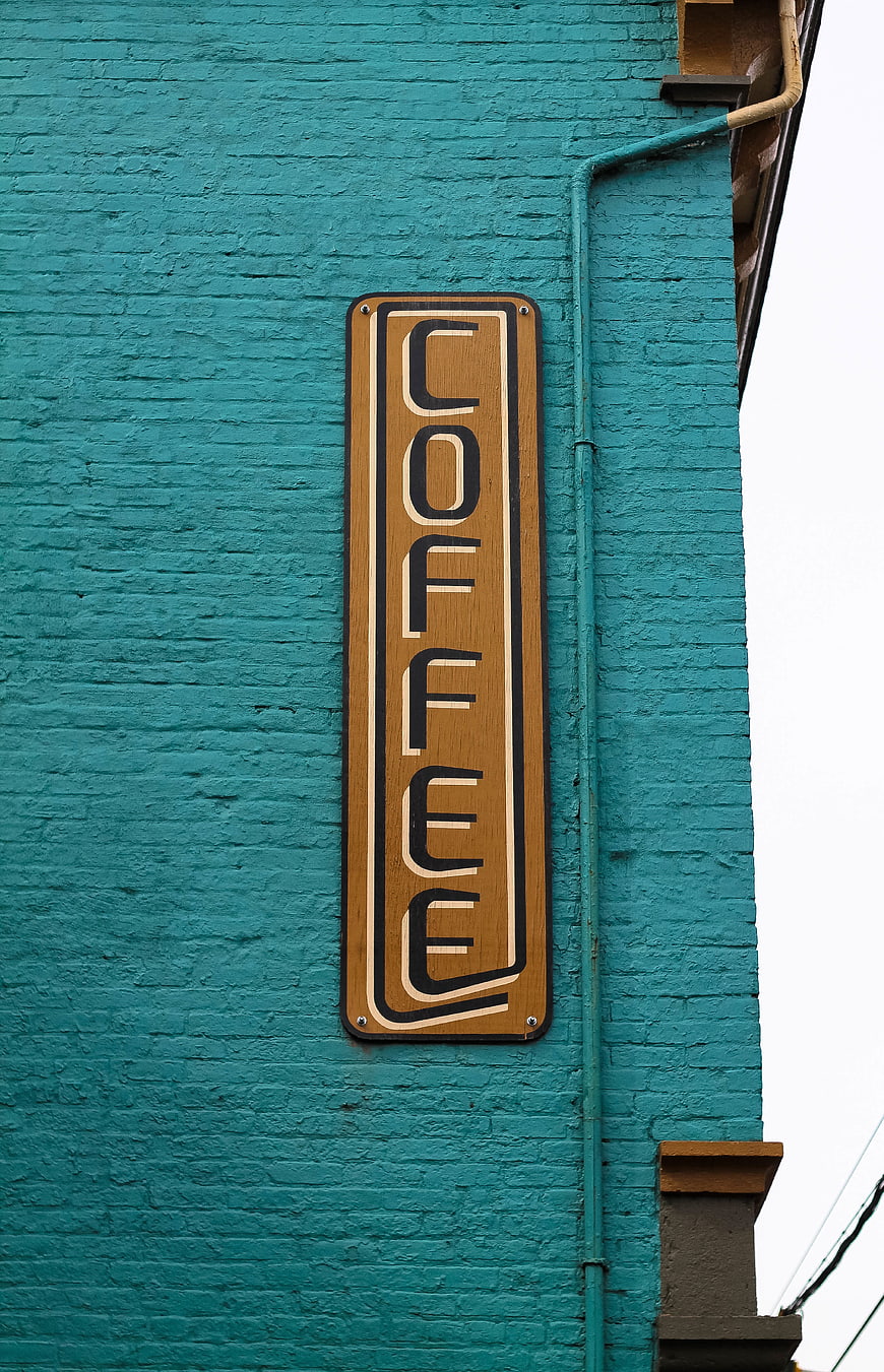 Vertical Coffee Sign on Teal Brick Wall