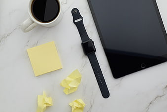 Flat lay of workspace with tablet, smartwatch, coffee, and sticky notes
