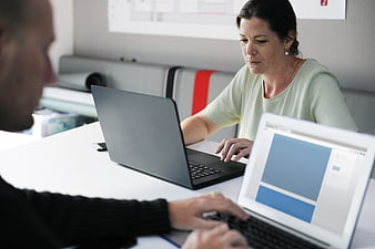 Colleagues working on laptops in modern office meeting