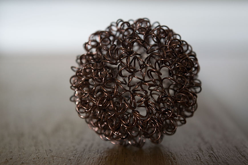 Close-up of copper wire mesh ball on wooden surface