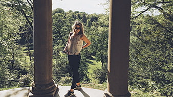 Blonde woman standing between pillars in a green forest