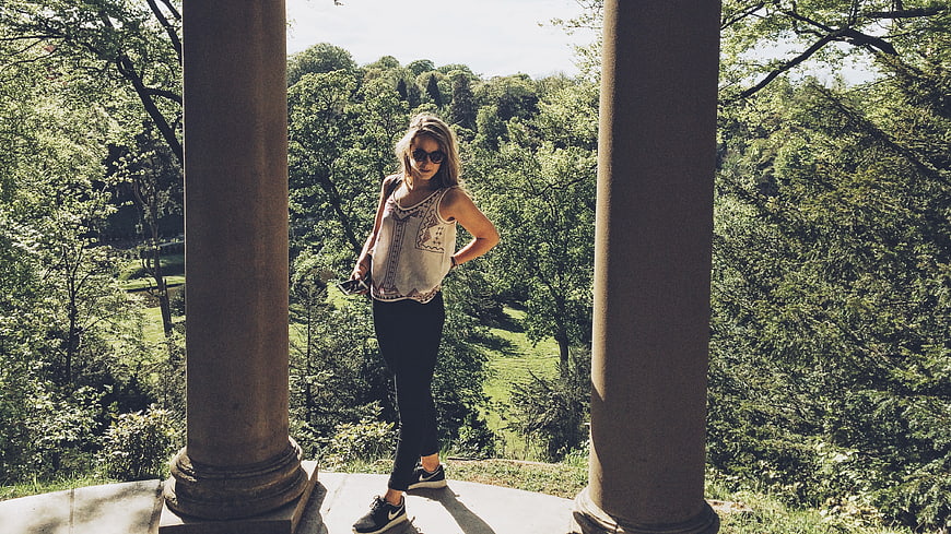 Blonde woman standing between pillars in a green forest
