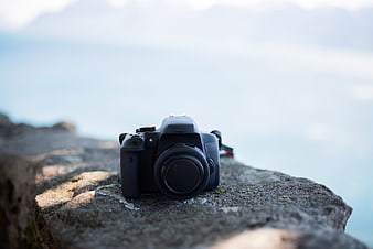 Black DSLR Camera on Rocky Cliff with Ocean View