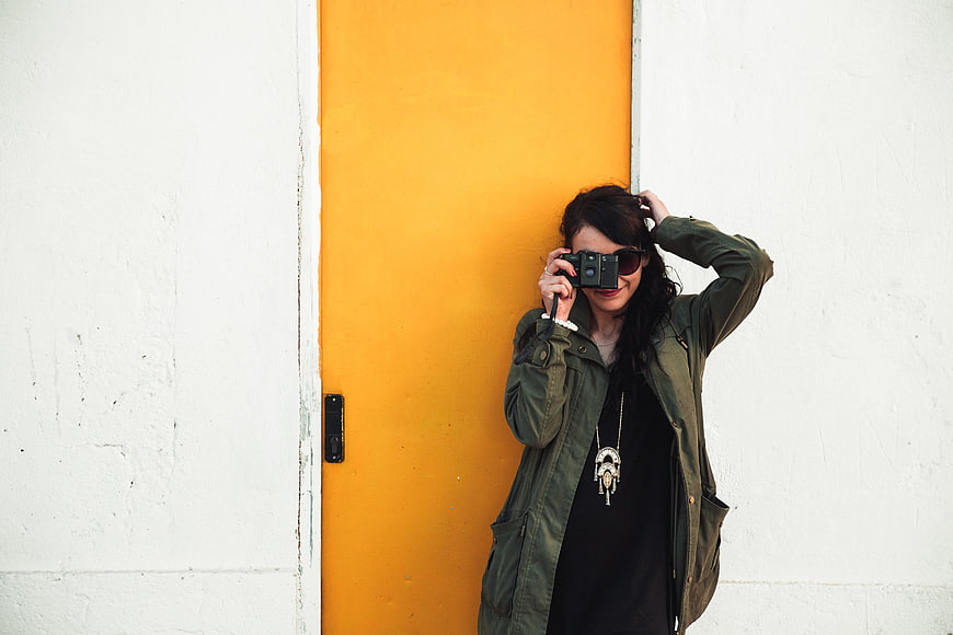 Woman with Camera Against Yellow Door