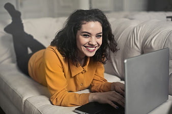 Happy Woman Lying on Couch Using Laptop