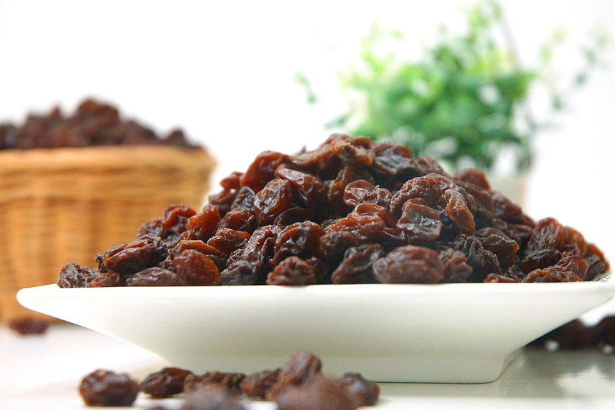 Pile of Dark Raisins in White Bowl