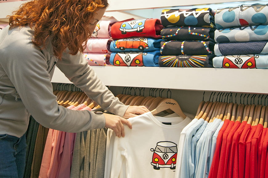 Woman shopping for colorful VW camper van t-shirts in boutique