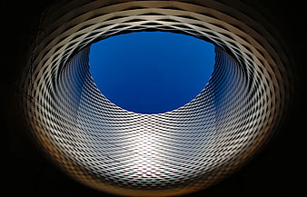 Abstract architectural view looking up through a circular metal mesh structure