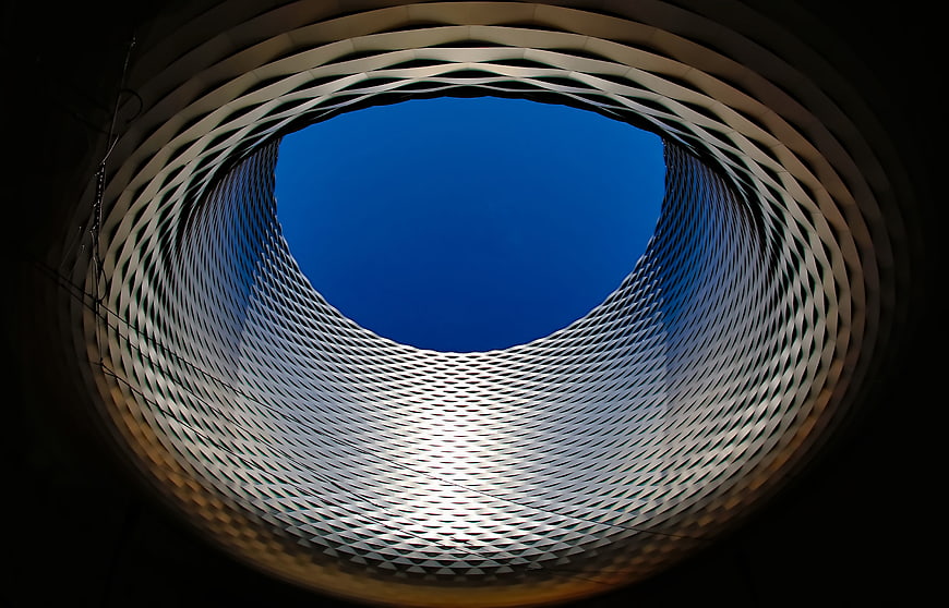 Abstract architectural view looking up through a circular metal mesh structure