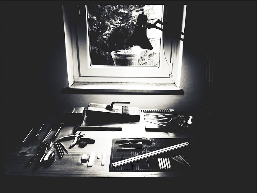 Black and white workshop desk with tools and window light