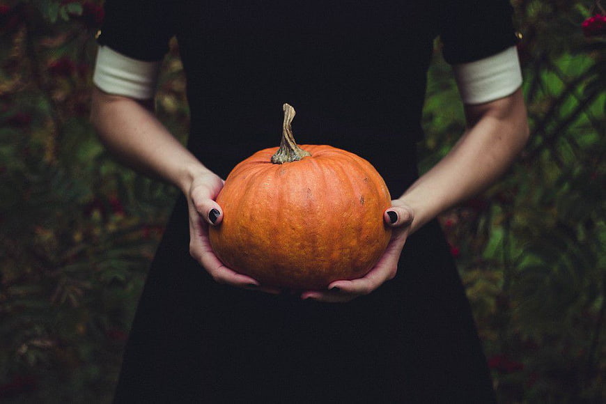 Woman in Black Dress Holding Orange Pumpkin