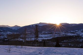 Sunburst over snow-covered mountains at sunrise
