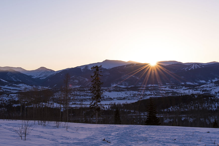 Sunburst over snow-covered mountains at sunrise