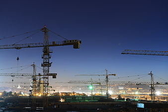 Construction cranes silhouetted against twilight city skyline