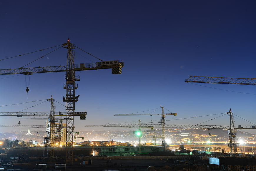 Construction cranes silhouetted against twilight city skyline