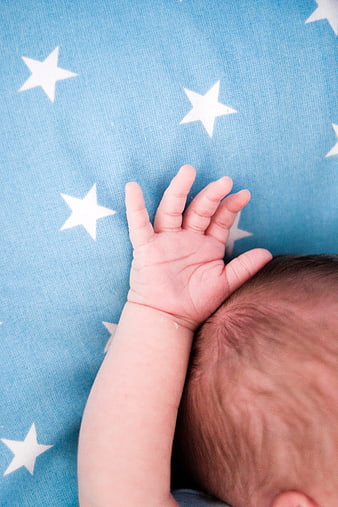 Newborn baby hand on blue star patterned blanket