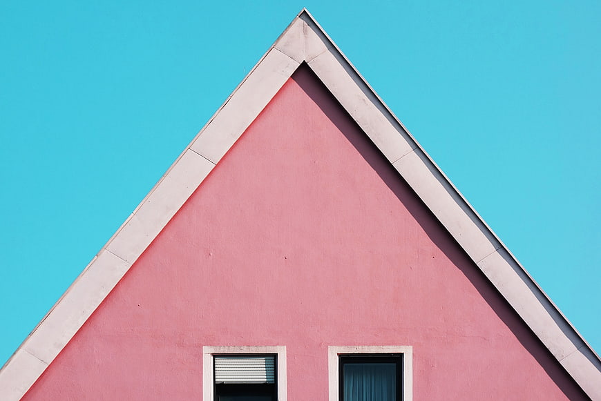 Pink triangular house facade against blue sky