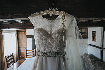 Lace wedding dress hanging in rustic cottage interior