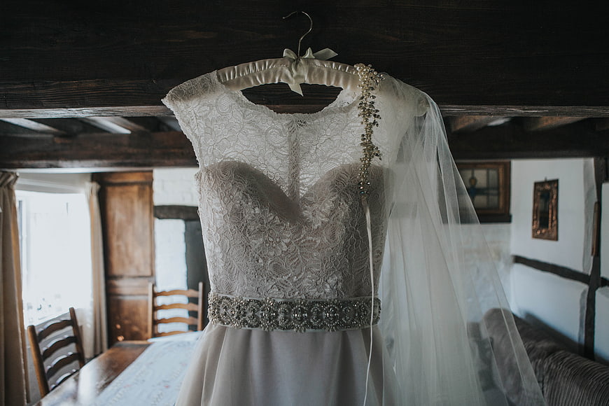Lace wedding dress hanging in rustic cottage interior