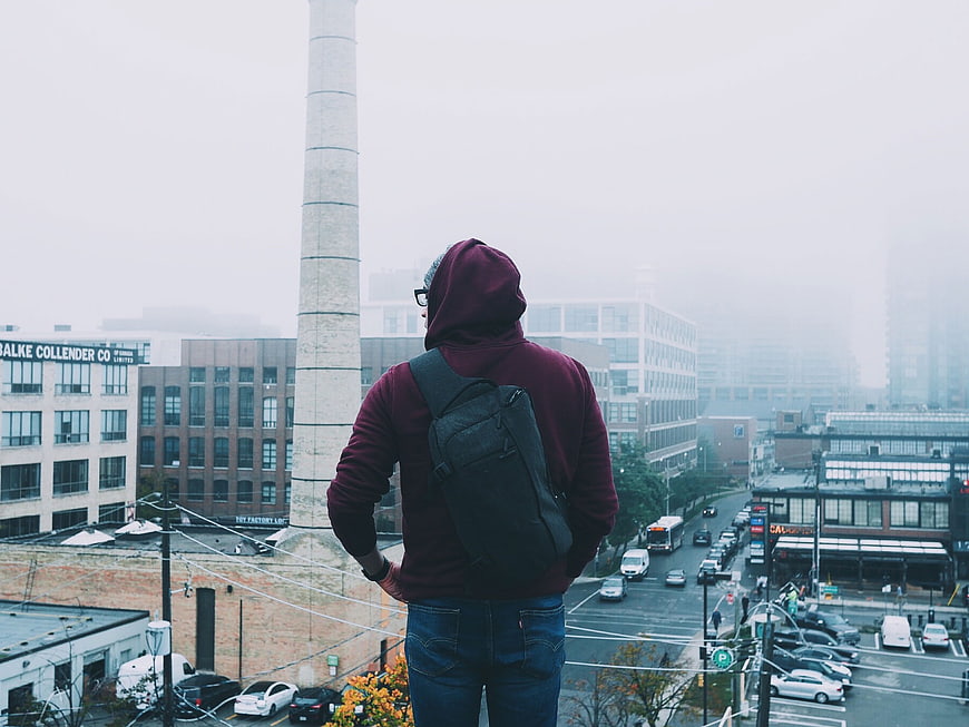 Man in Hoodie Looking at Foggy City Skyline