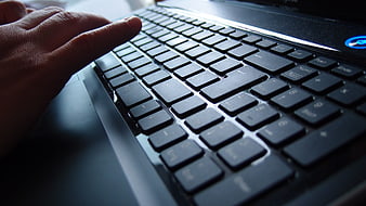 Close-up of hand typing on laptop keyboard