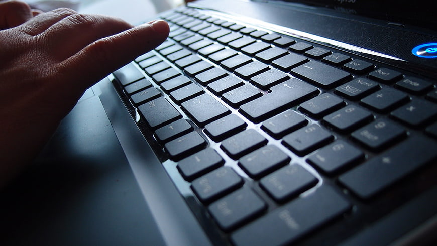 Close-up of hand typing on laptop keyboard