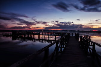 Silhouetted Wooden Pier at Sunset Over Calm Water