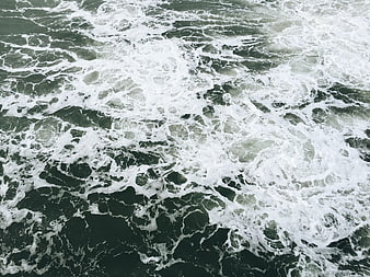 Aerial view of turbulent ocean waves with white sea foam