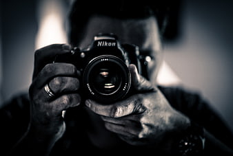 Man holding Nikon camera in black and white mirror selfie