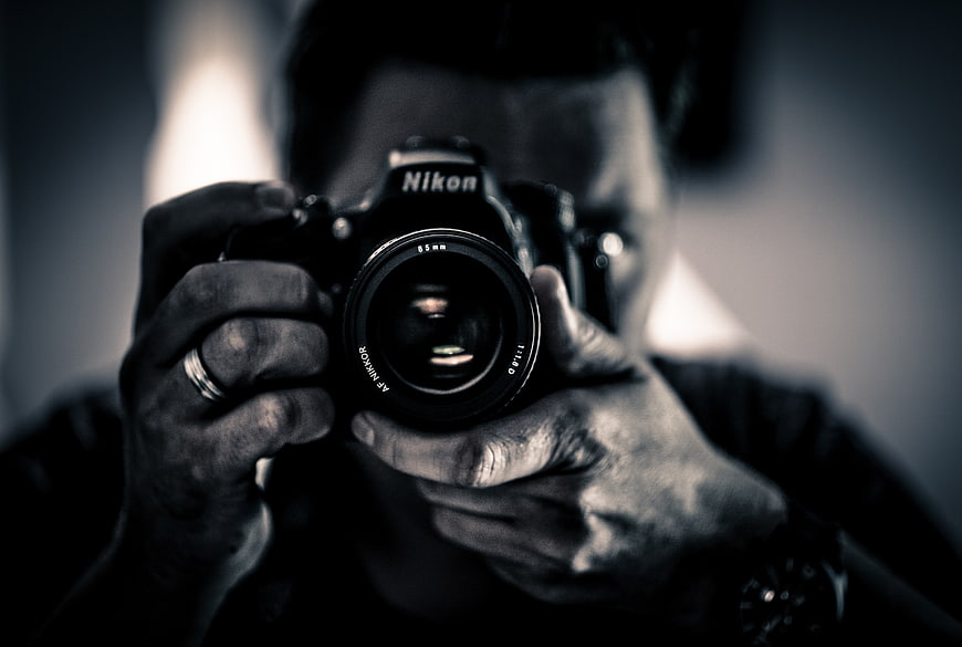 Man holding Nikon camera in black and white mirror selfie