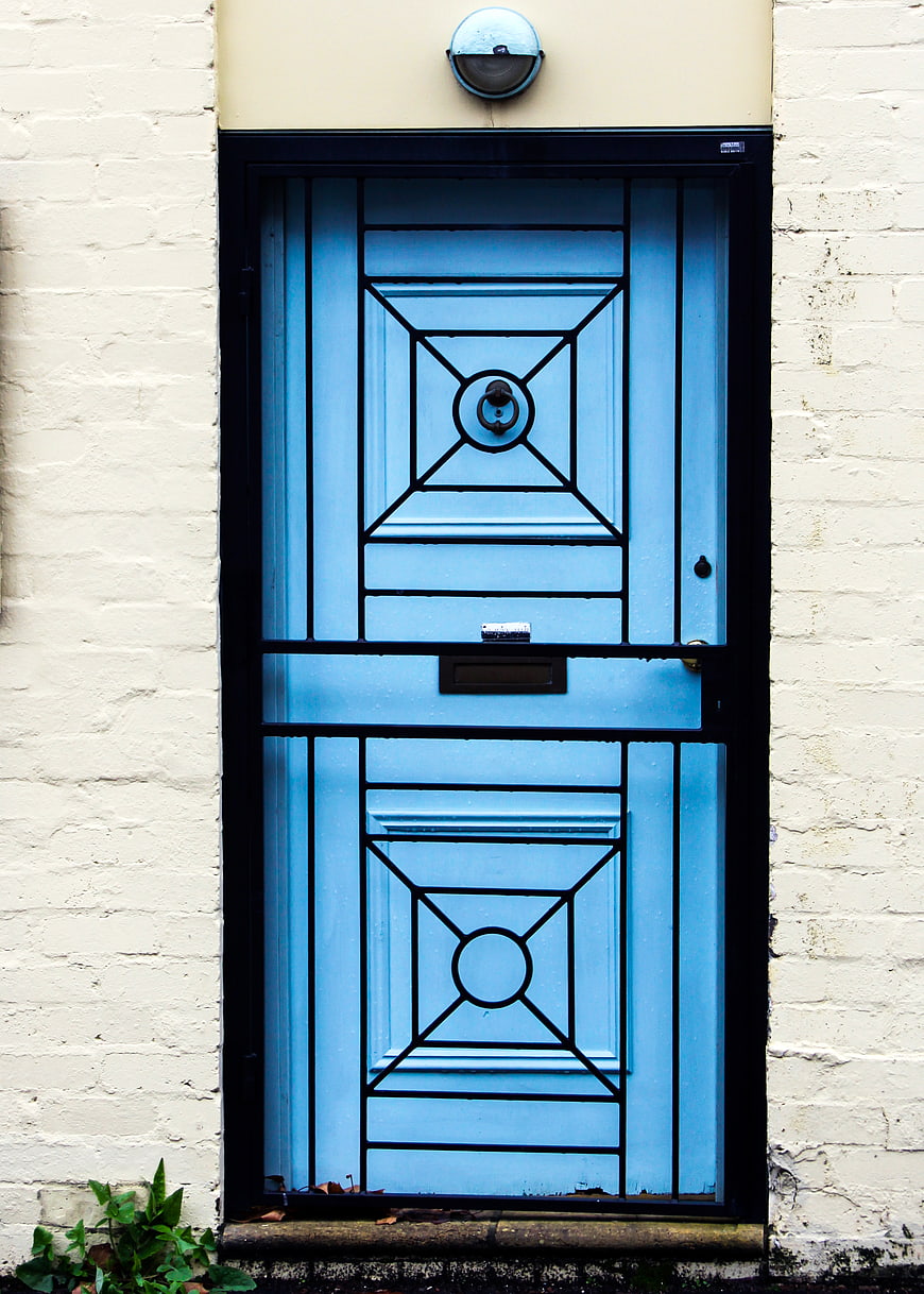 Blue Front Door with Black Security Gate on White Brick Wall