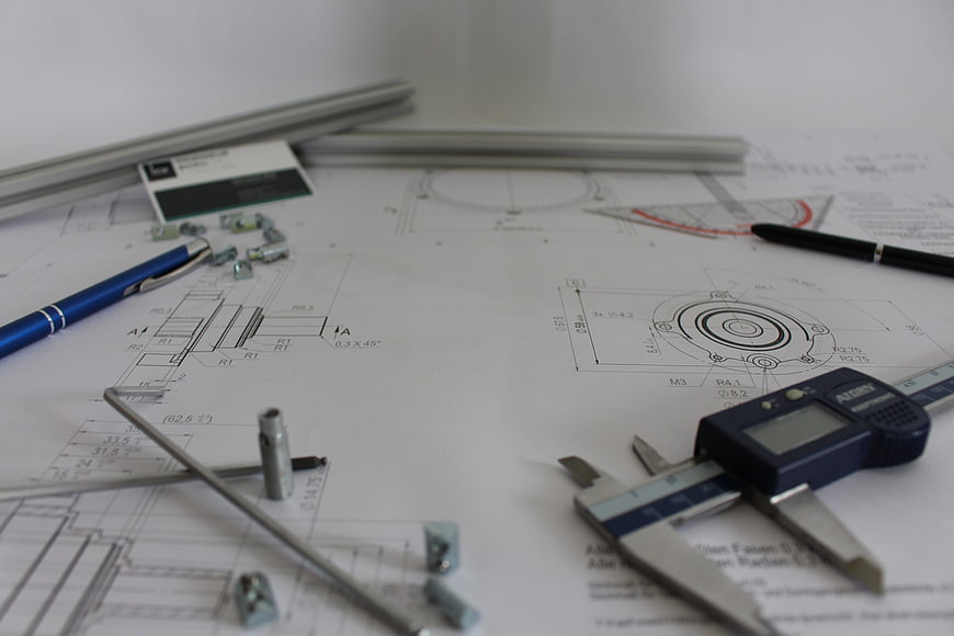 Engineering blueprints with digital calipers and tools on desk