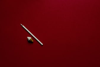 White pencil and miniature ice cream cone on red background