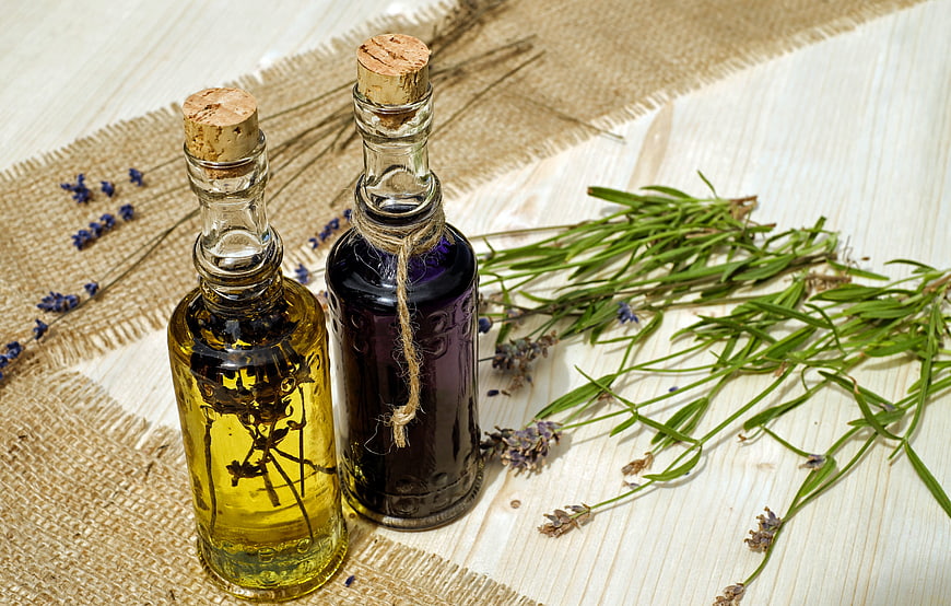 Natural aromatherapy oils with lavender and rosemary on rustic wood