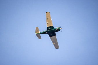 Green Propeller Airplane Flying in Blue Sky