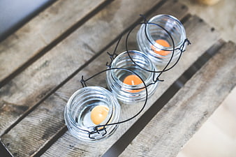 Three glass tealight holders on rustic wooden slats
