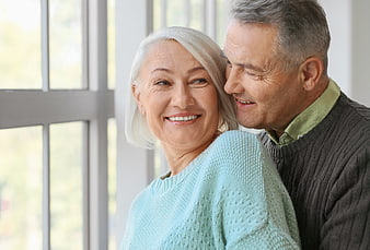 Happy Senior Couple Embracing Indoors by Window