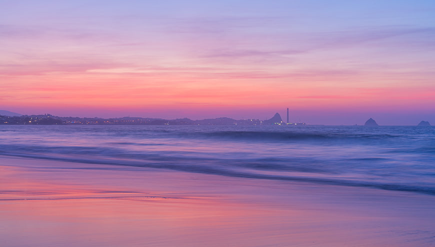Serene pastel sunset beach landscape with smooth ocean waves