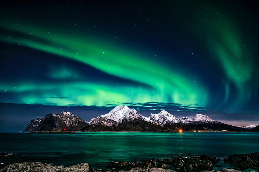 Vibrant Green Aurora Borealis Over Snowy Mountains and Ocean