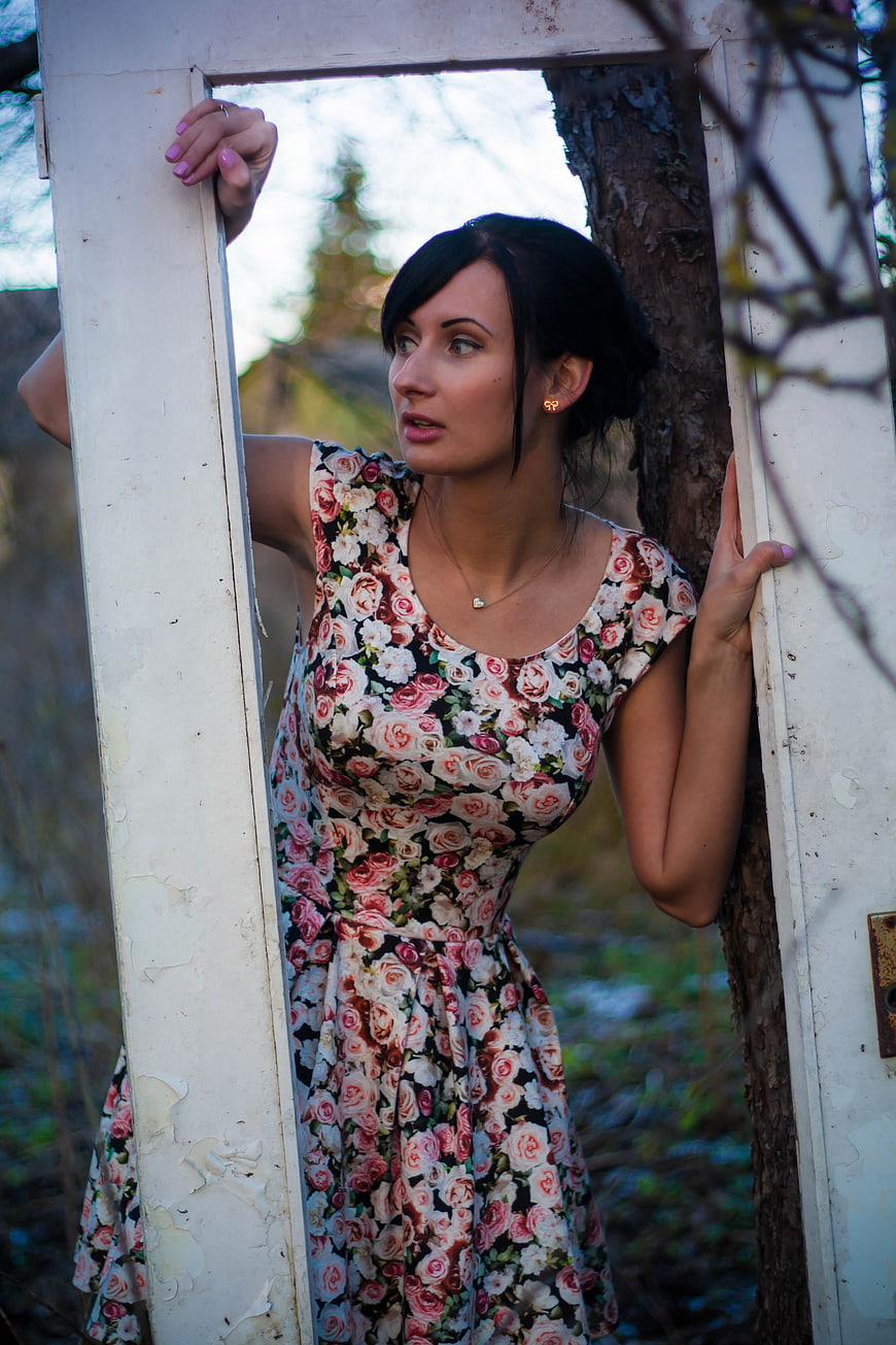 Woman in Floral Dress Holding Old White Door Frame