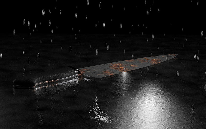 Rusty kitchen knife lying on wet surface with raindrops