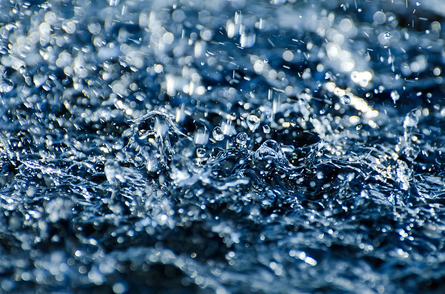 Close-up of splashing blue water droplets and ripples