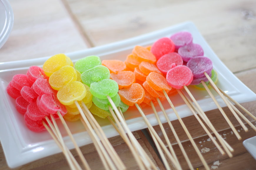 Colorful fruit gummy candy skewers on white plate