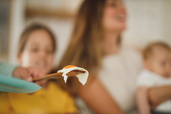 Fried egg on wooden spatula with blurred family background