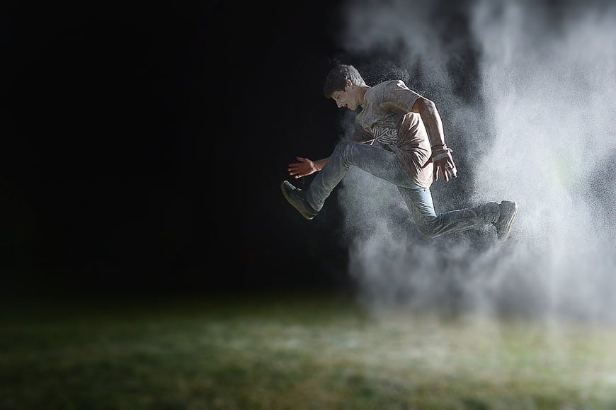 Man Jumping Through Smoke in Dark Night