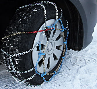 Car tire with snow chains installed on snowy winter road