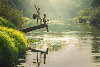 Two boys fishing on a log in a river